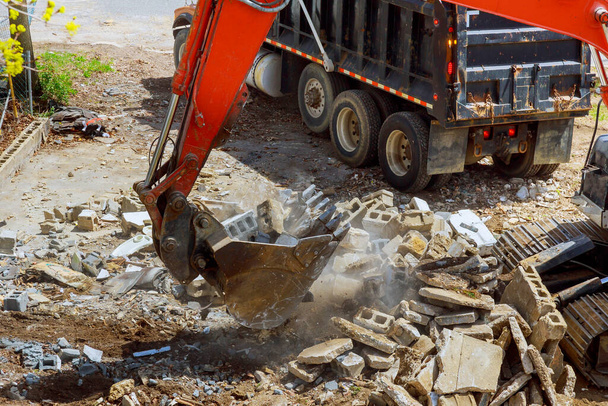 Экскаватор загружает строительные отходы в материал для утилизации при строительстве, ремонте или обслуживании дома
 - Фото, изображение