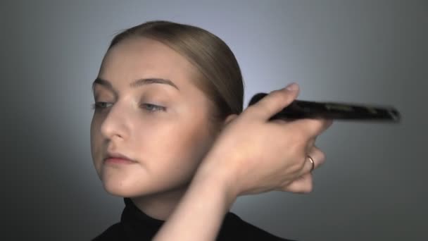 Meikki taiteilija tekee ammatillinen meikki nuori nainen kauneushoitola. Make up Taiteilija soveltaa jauhetta suurella harjalla - Materiaali, video