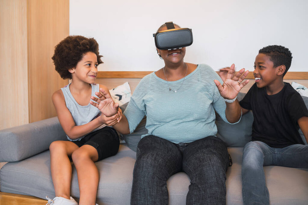Portrait of African American grandmother and grandchildren playing together with VR glasses at home. Family and technology concept. - Photo, image