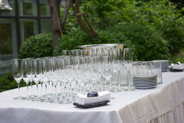 Fiestas de mesa festiva. Vasos y platos vacíos al aire libre. Banquete en la terraza. Restaurante en la naturaleza. Cuadro de configuración
. - Foto, imagen
