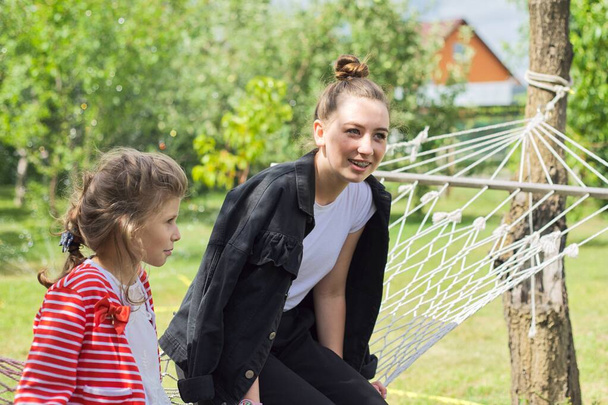 Meninas irmãs adolescentes e criança se divertindo na rede no jardim do quintal, meninas felizes rindo
 - Foto, Imagem