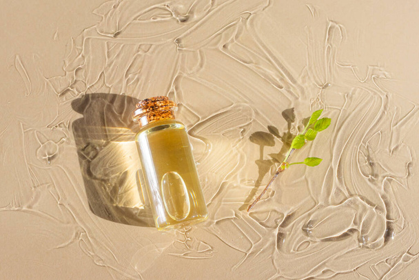Natürliche ätherische Öle und Zweige mit frischen grünen Blättern liegen auf einem Glas mit einem transparenten Kosmetikgel. Modernes Apothekenkonzept. Neutrale Farben. Flache Lage, Blick von oben. - Foto, Bild