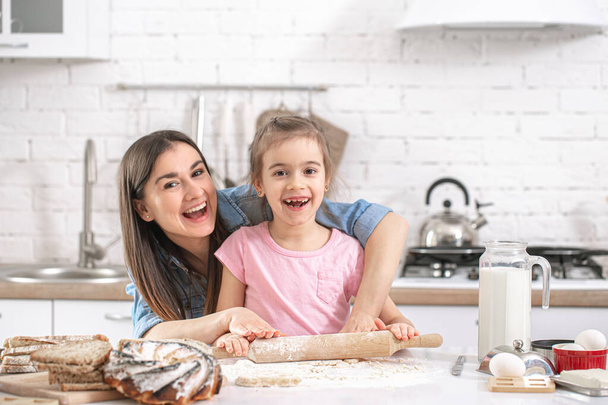 Familia feliz. Mamá e hija preparan pasteles en la cocina. El concepto de familia amorosa y valores familiares. Comida casera saludable
. - Foto, imagen