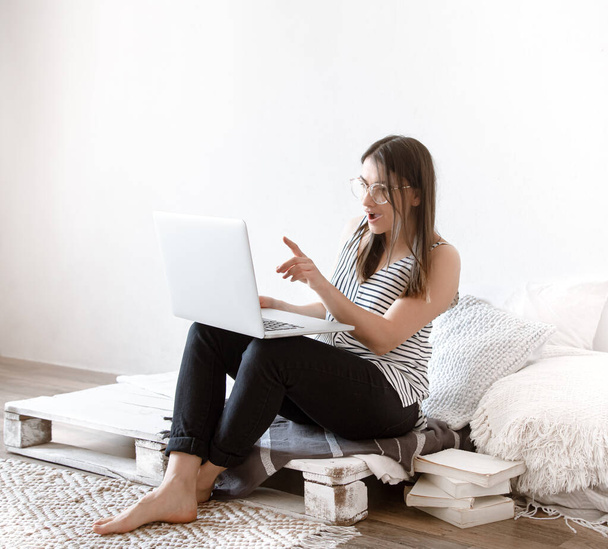 Mladá žena pracuje doma na dálku u počítače. Freelancer a práce na internetu. - Fotografie, Obrázek