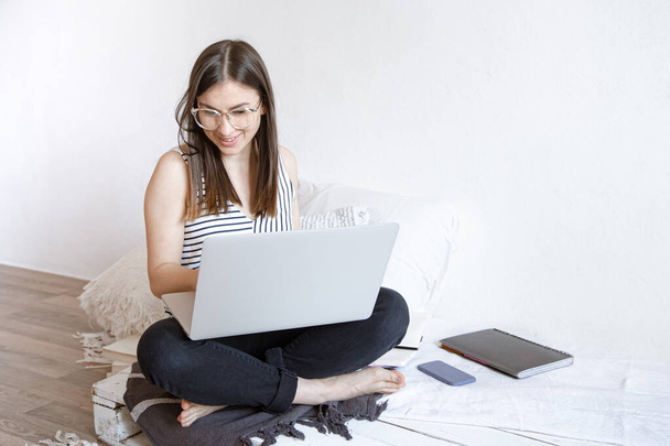 Une jeune femme travaille à distance sur un ordinateur à la maison. Freelance et travail sur Internet
. - Photo, image