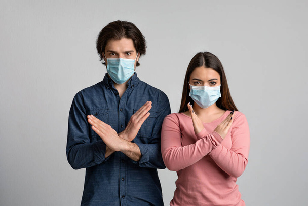 Остановить вспышку коронавируса. Молодая пара в медицинских масках со скрещенными руками
 - Фото, изображение