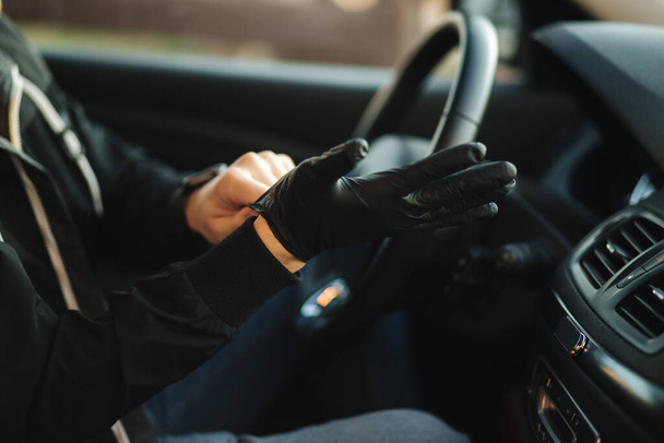 Man in car put on black gloves to protect himself - Fotoğraf, Görsel