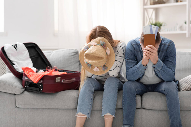 Відчайдушна пара страждає вдома біля упакованої валізи для відпустки
 - Фото, зображення