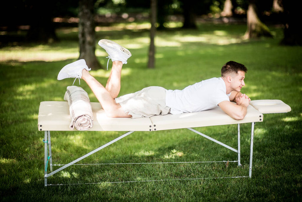 uomo con lettino per massaggi all'esterno, soggiorno sull'erba verde
 - Foto, immagini
