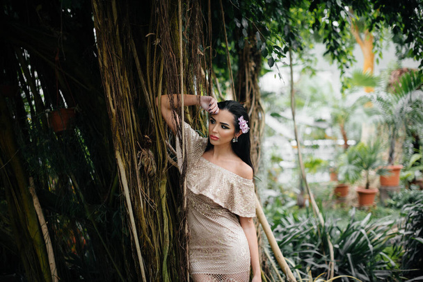Egy fiatal, gyönyörű barna nő pózol sűrű dzsungel és esőerdő között. Gyógyfürdő - Fotó, kép