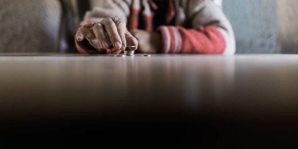 Wide view image of senior man counting his last euro coins in a conceptual image of lack and poverty. - 写真・画像