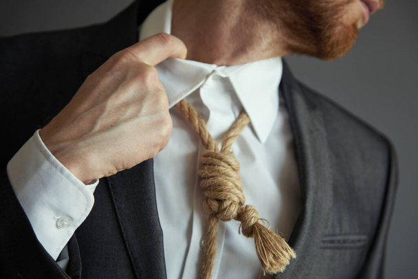 Concept image of business in trouble. Man in suit with Lynch loop instead of tie over neck. - Photo, Image