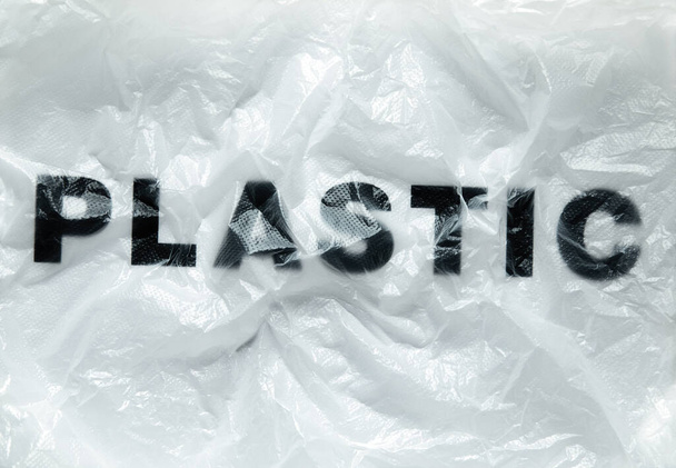 Czarne plastikowe słowo na przezroczystej białej jednorazowej plastikowej torbie. Koncepcja problemu zanieczyszczenia środowiska obraz z miejsca kopiowania - Zdjęcie, obraz