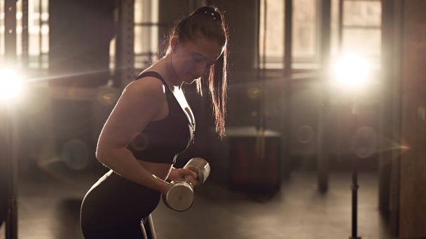 Candid strong young woman is training with a dumbbells in the gym. Real wokout - Fotó, kép