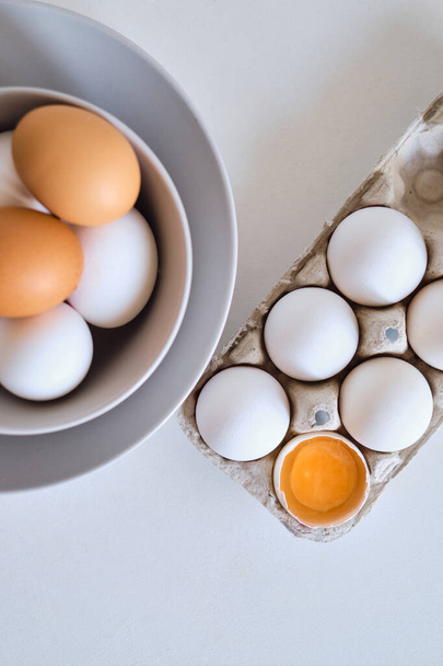 Chicken eggs on minimalist plates. Art photo with uncooked eggs on white table. Natural organic farm product. Preparing for Easter holiday. Kitchen art, dish on cuisine. Raw ingredient for cooking eat - Foto, Imagen