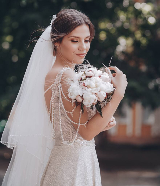 Krásná mladá nevěsta v bílých svatebních šatech pózuje venku - Fotografie, Obrázek