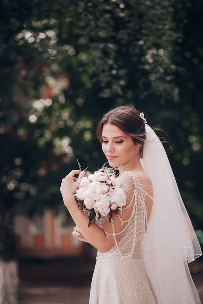 Gyönyörű fiatal menyasszony fehér esküvői ruha pózol szabadban - Fotó, kép