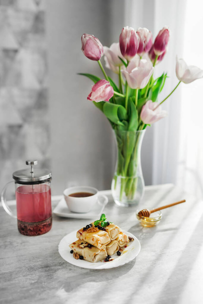 holiday morning. pancakes with tea and a bouquet of tulips on the table. Shrovetide - Photo, Image