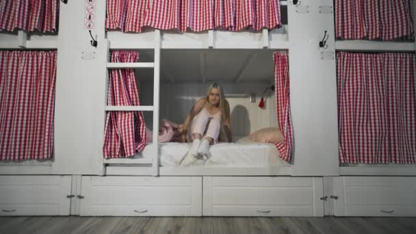 Fiatal nő felébred a kényelmes hostel szobában - Felvétel, videó