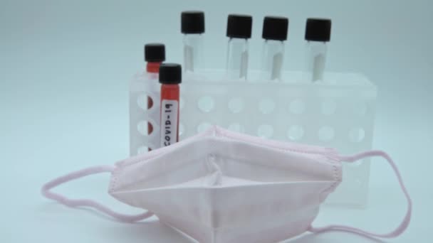 4K, maska twarzy i probówka z zakażoną próbką krwi dla COVID-19, koronawirusa znalezionego w Wuhan w Chinach. Badania nad szczepionką dla wirusa 2019-nCoV. Koncepcja zwalczania zakaźnych chorób zakaźnych - Dan - Materiał filmowy, wideo