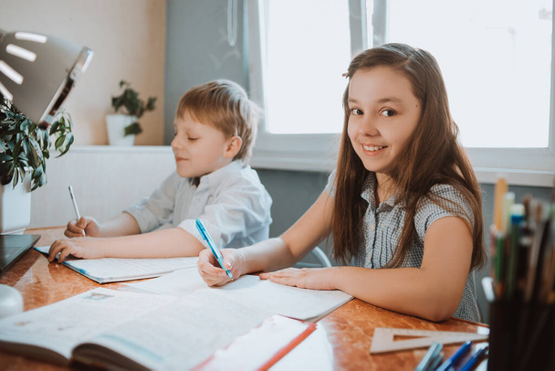 Tyttö ja poika kirjoittavat heille läksyjä kotona CoVid-19 karanteenin aikana, etäopiskelu verkossa kannettavan tietokoneen kanssa, lapsi tekee läksyjä kouluun. Lapset jäivät kotiin
. - Valokuva, kuva