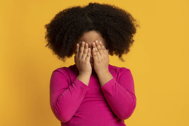 Маленька афроамериканська дівчинка плаче і прикриває очі руками
 - Фото, зображення