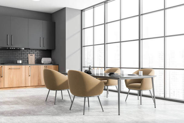 Corner of panoramic kitchen with gray and brick walls, concrete floor, wooden countertops, grey cupboards and dining table with beige armchairs. Blurry cityscape. 3d rendering - Valokuva, kuva