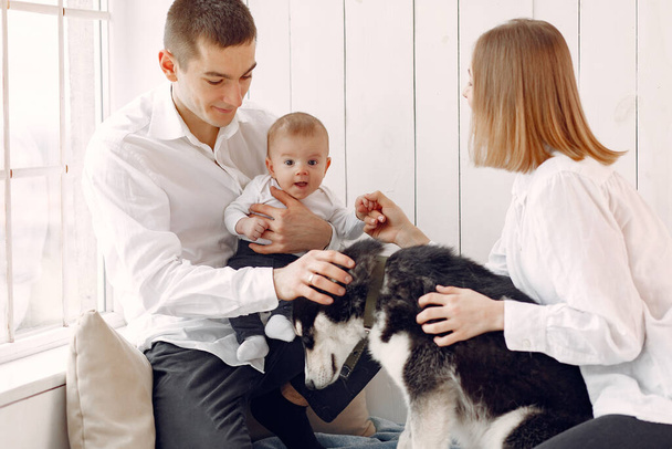 Beautiful family spend time in a bedroom with a dog - Фото, зображення