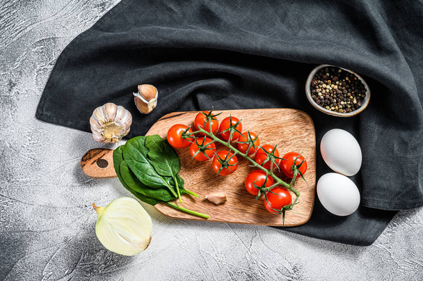 Ingredientes para cocinar Shakshuka. Huevos, cebollas, ajo, tomates, pimientos, espinacas. Fondo gris. Vista superior. - Foto, imagen