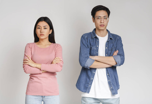 Upset asian man and woman posing over grey background - Photo, Image