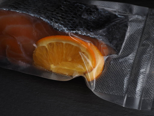 Somon fileto, portakal dilimleriyle marine edilmiş, vakum paketinde. - Fotoğraf, Görsel