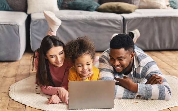 Międzynarodowa rodzina na podłodze ogląda laptop - Zdjęcie, obraz