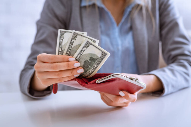 Make money at quarantine. Woman puts dollars in wallet - Фото, изображение