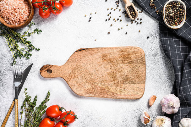 Wooden cutting board in center of Fresh raw greens, vegetables. Healthy, clean eating, vegan, dieting food concept. White background. Top view. Copy space. - Photo, Image