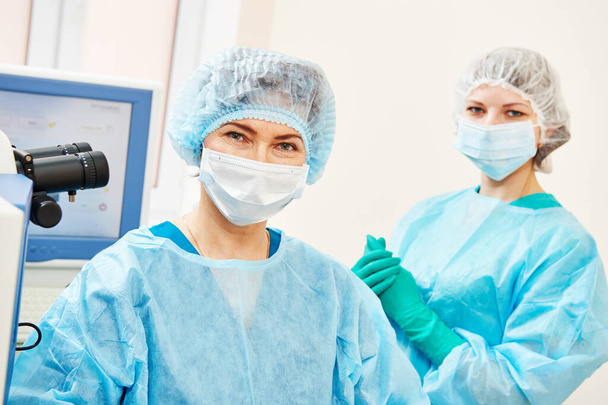 female surgeon with assistant in ophthalmological operation room - Φωτογραφία, εικόνα