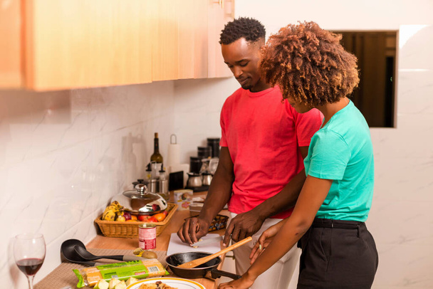 Black African American couple preparing food in the kitchen - Фото, изображение