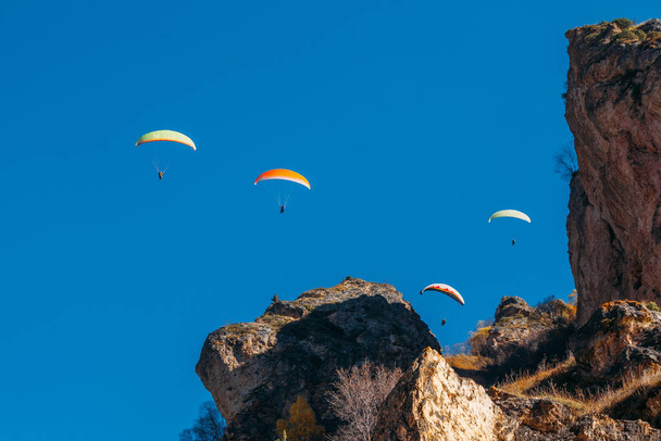 Flying of paragliders above autumn rocky mountains. - Фото, зображення
