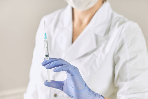 Siringa con un medicinale in mano di un'infermiera con un cappotto bianco
 - Foto, immagini