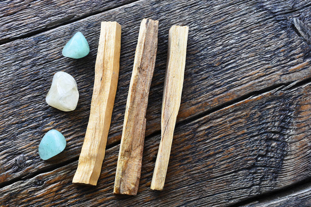 A close up image of three palo santo smudge sticks with green aventurine and citrine healing crystals.  - Photo, Image