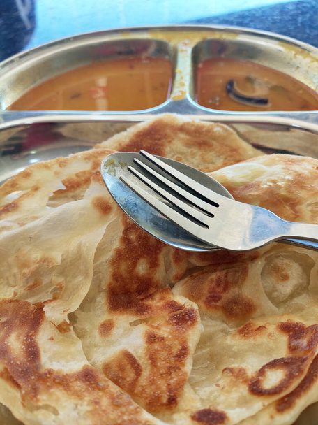 Traditional Malaysian signature flatbread food called roti canai.  This is type of pancake made from mix of flour, egg and water. Eat with special sauce. Normally combined with the teh tarik drinks.  - Photo, Image