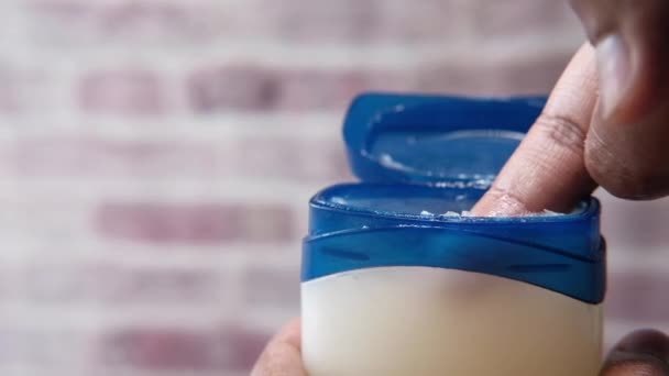  άνθρωπος χέρι χρήση λευκό ζελέ πετρελαίου σε μπλε φόντο  - Πλάνα, βίντεο