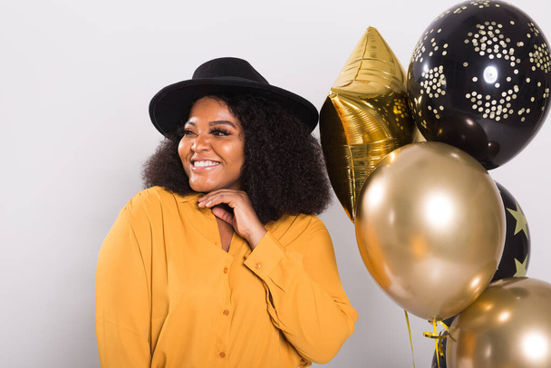Vacaciones, fiesta de cumpleaños y concepto de diversión - Retrato de la joven mujer joven afroamericana sonriente con estilo en el fondo blanco celebración de globos
. - Foto, imagen