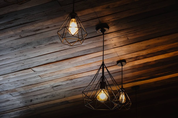 House interior of loft and rustic style. Beautiful vintage luxury light bulb hanging decor glowing in dark. Retro filter effect style. Blend of history and modern. - Foto, afbeelding