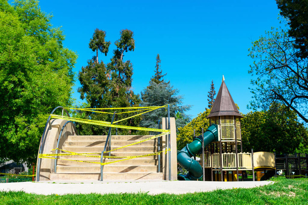Kinderspielplatz im Freien mit gelbem Absperrband abgegrenzt, um unbeabsichtigtes Betreten zu verhindern - Foto, Bild