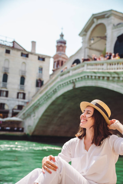 woman sitting near rialto bridge in venice italy looking at grand canal with gondolas summer time copy space - Foto, imagen