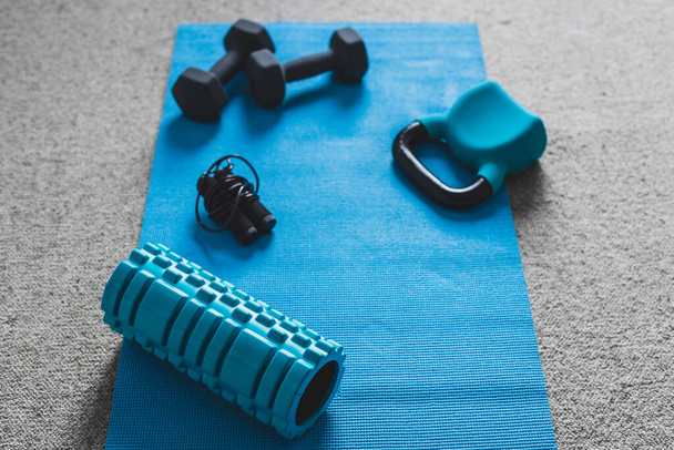 home gym concept, room with dumbbells kettlebell foam roller and push-up handles on yoga mat to workout from home - Fotoğraf, Görsel