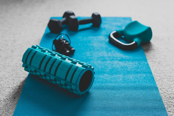home gym concept, room with dumbbells kettlebell foam roller and push-up handles on yoga mat to workout from home - Fotografie, Obrázek
