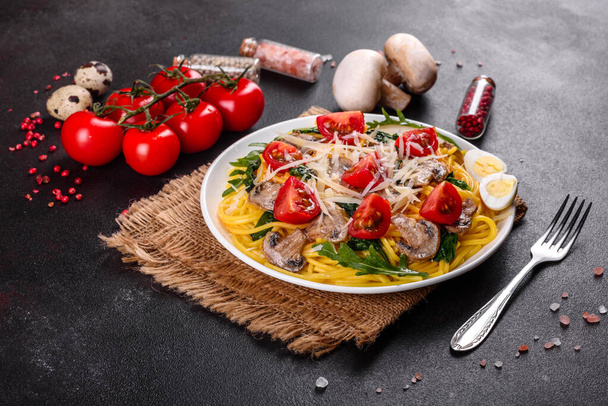 Spagetti gombával, sajttal, spenóttal, rukkolával és meggyparadicsommal. Olasz étel, mediterrán kultúra - Fotó, kép