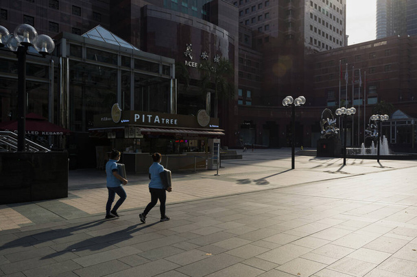 SINGAPORE, SINGAPORE - APR 10, 2020: Workers walking along an empty street of Orchard Road, Singapore during Circuit Breaker or Lockdown due to increased rate of COVID-19 Infection - 写真・画像