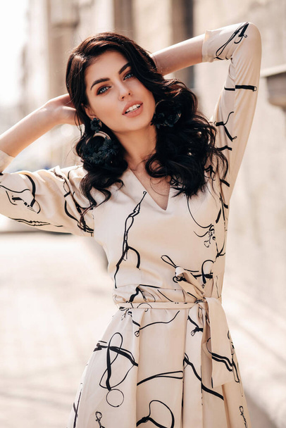 fashion outdoor photo of beautiful woman with dark hair in elegant clothes posing in the spring street - Valokuva, kuva